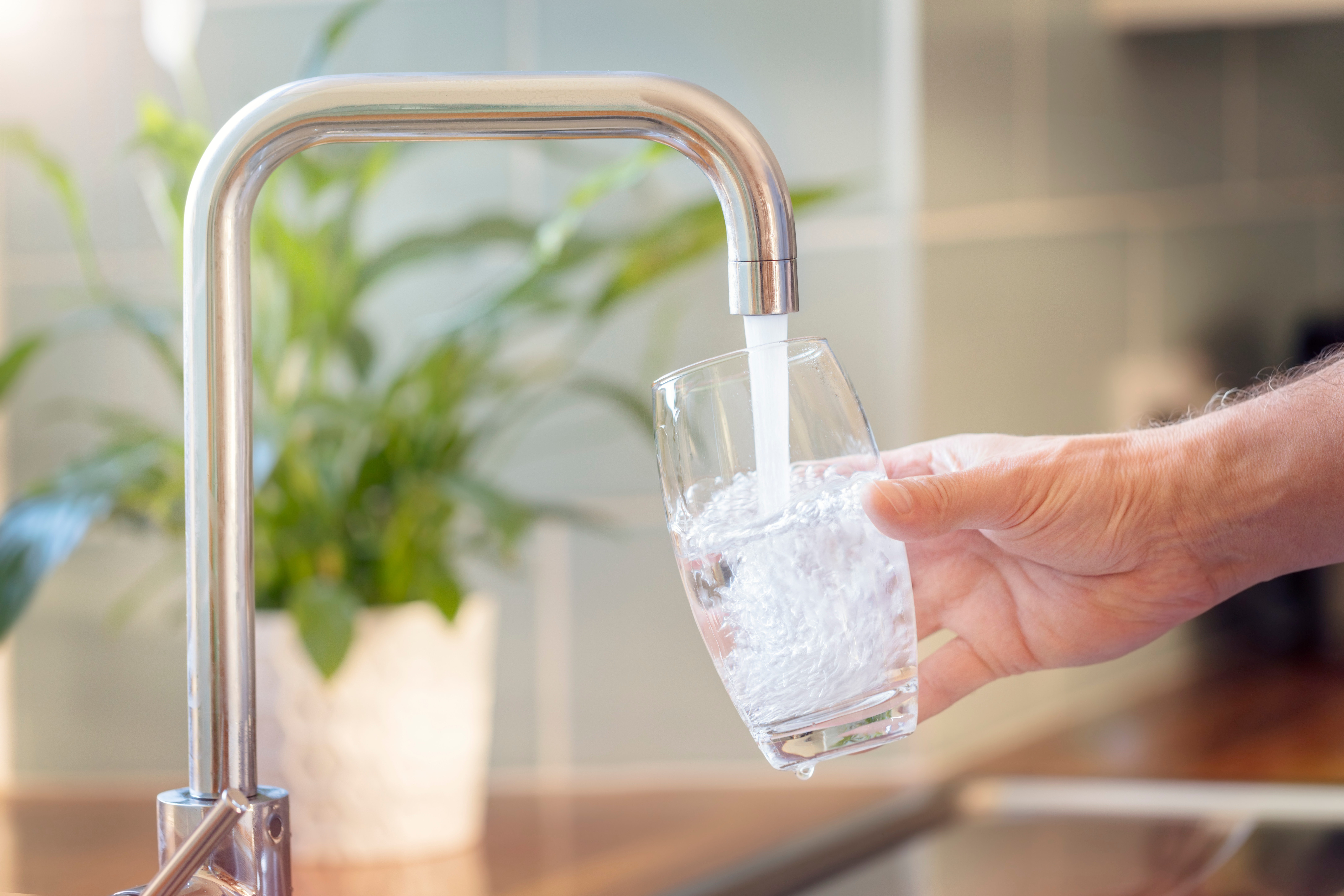 A flowing water faucet providing water to a person in their home. 
